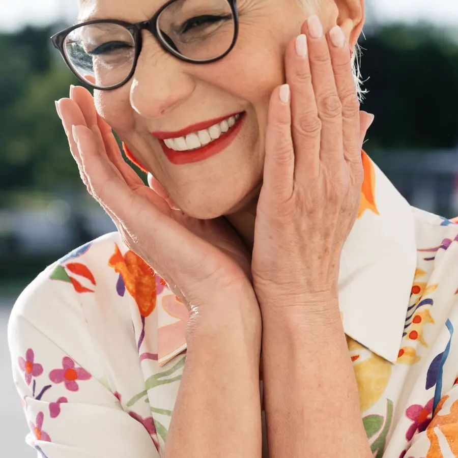 Mulher madura sorrindo com as mãos no rosto