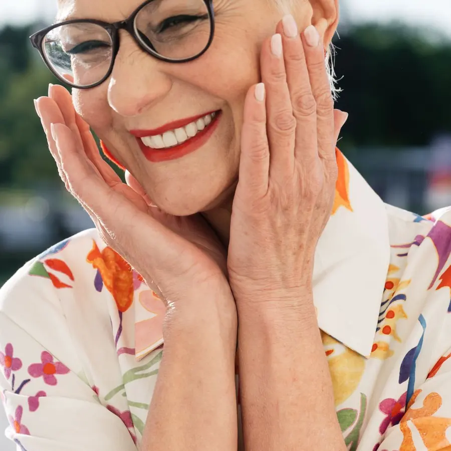 Mulher madura sorrindo com as mãos no rosto